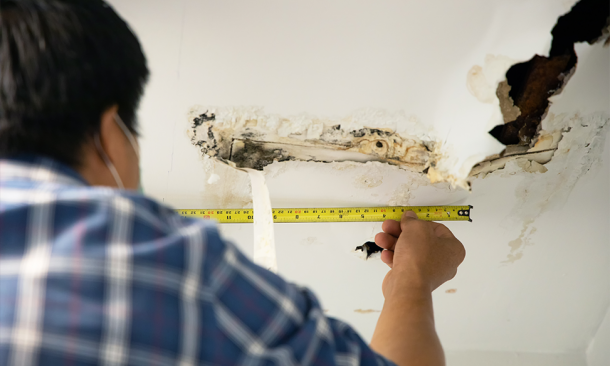 Contractor measuring water damage on ceiling