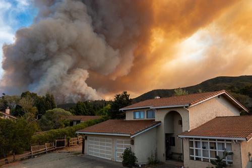 House in front of hill struck by large wildfire