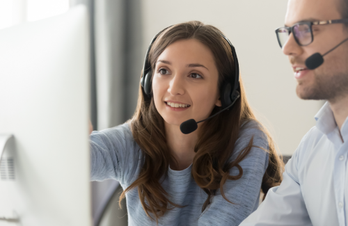 2 agents in headphones, reviewing something on computer