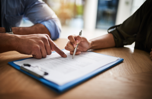 Two people sitting at desk, reviewing and signing forms