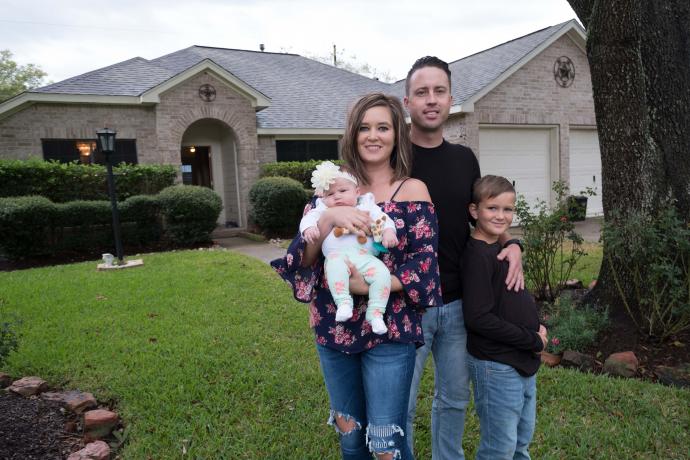 Image depicting a family standing outside their home