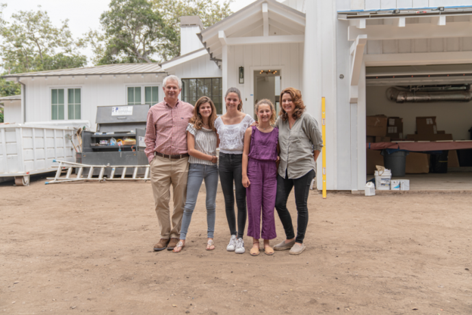 A picture of a family standing outside of a house.