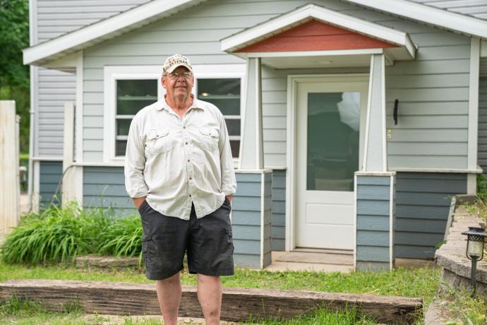 An image of a man standing outside of a house.