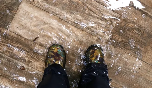Downward shot of person's feet standing on flooded vinyl floor