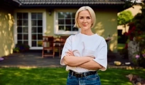 Smiling woman standing in front yard of house
