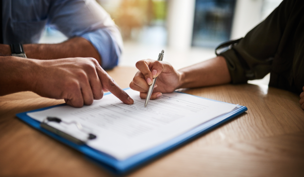 Two people sitting at desk, reviewing and signing forms